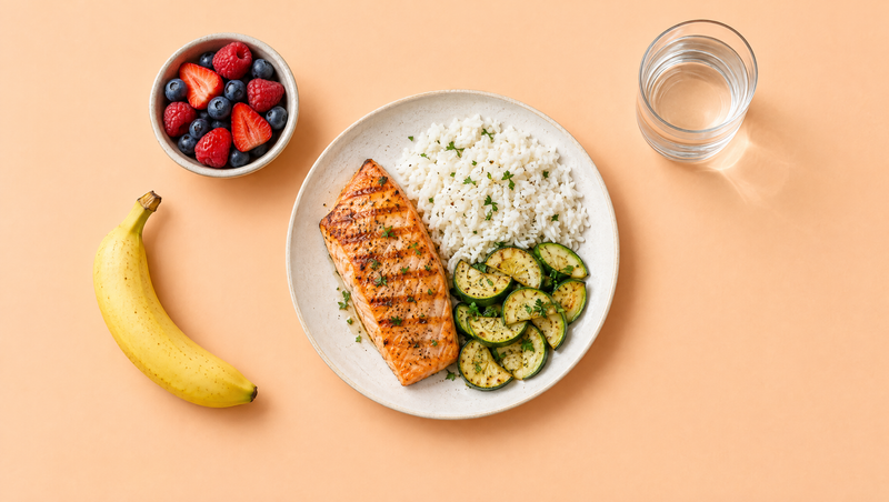 Plate of salmon, rice and zucchini with a banana and berries