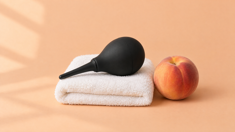 A black douche bulb on a folded white towel beside a ripe peach